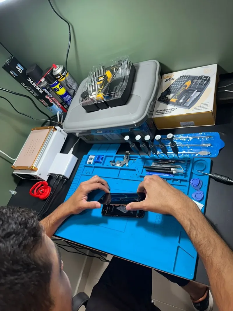 Profissional da Campeche Cell trabalhando em um celular na bancada